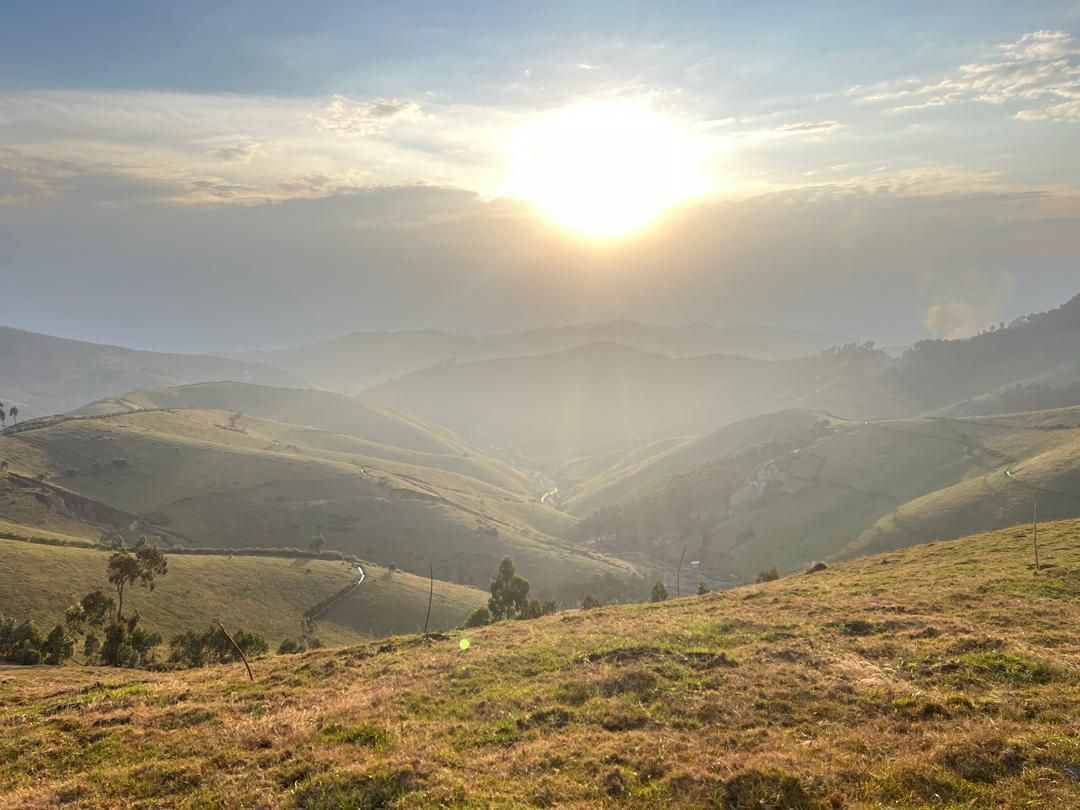 Steep grass-covered ridges and a deep valley in Kabaya, photographed in warm evening light
