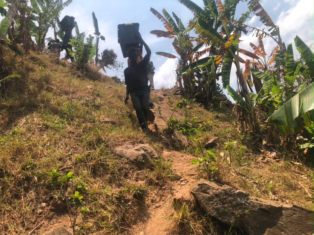 Field team member carrying equipment uphill